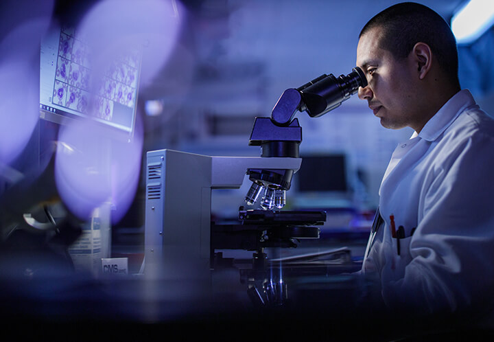 Healthcare professional looking through microscope