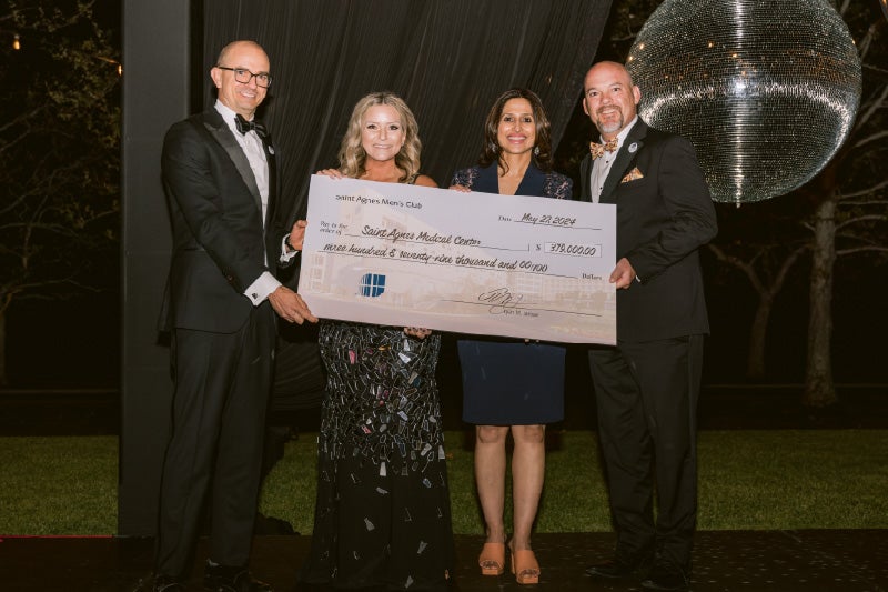 mens club holding check with saint agnes leadership