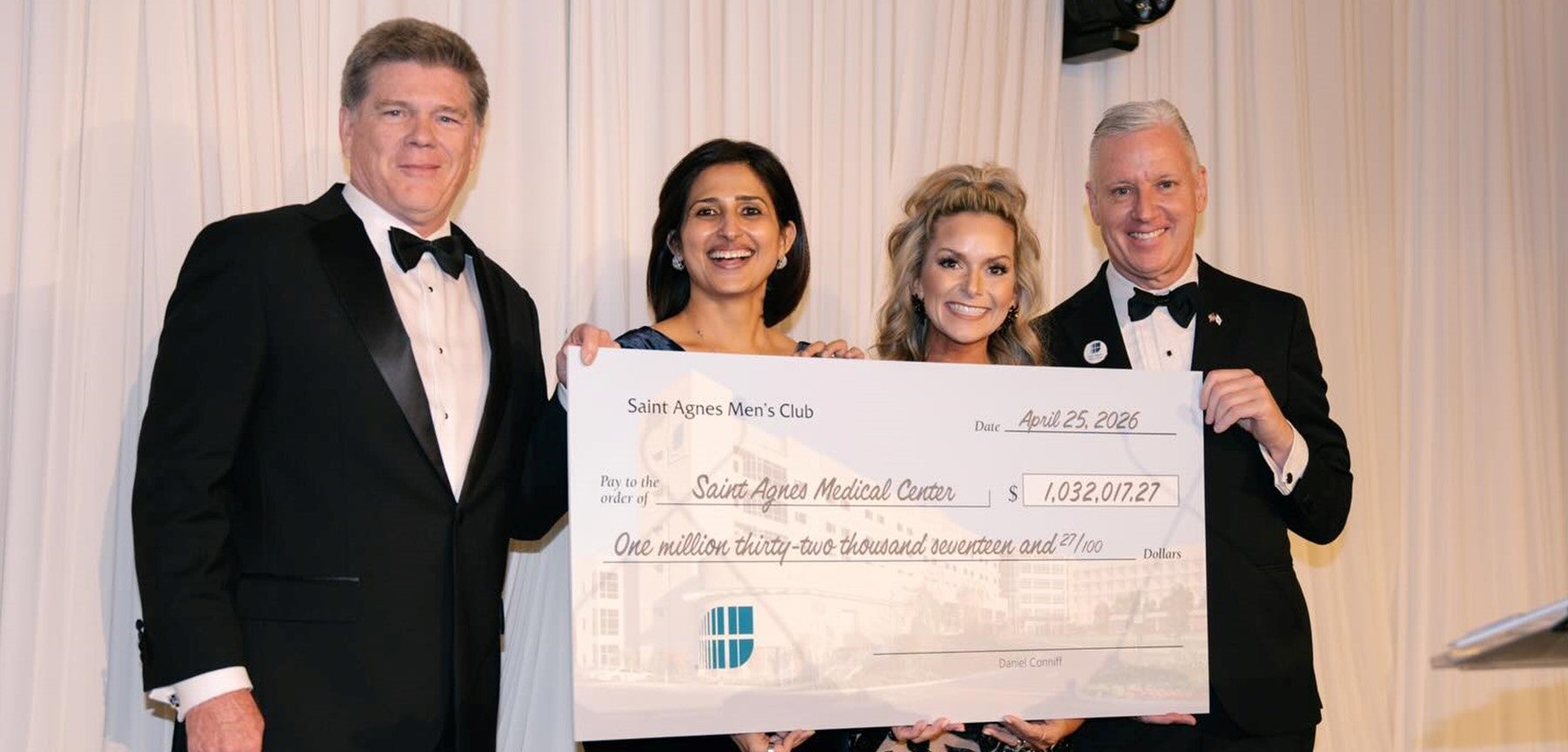Four people holding large check