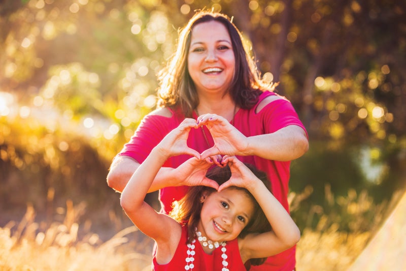 Mom and daughter holding up heart hands